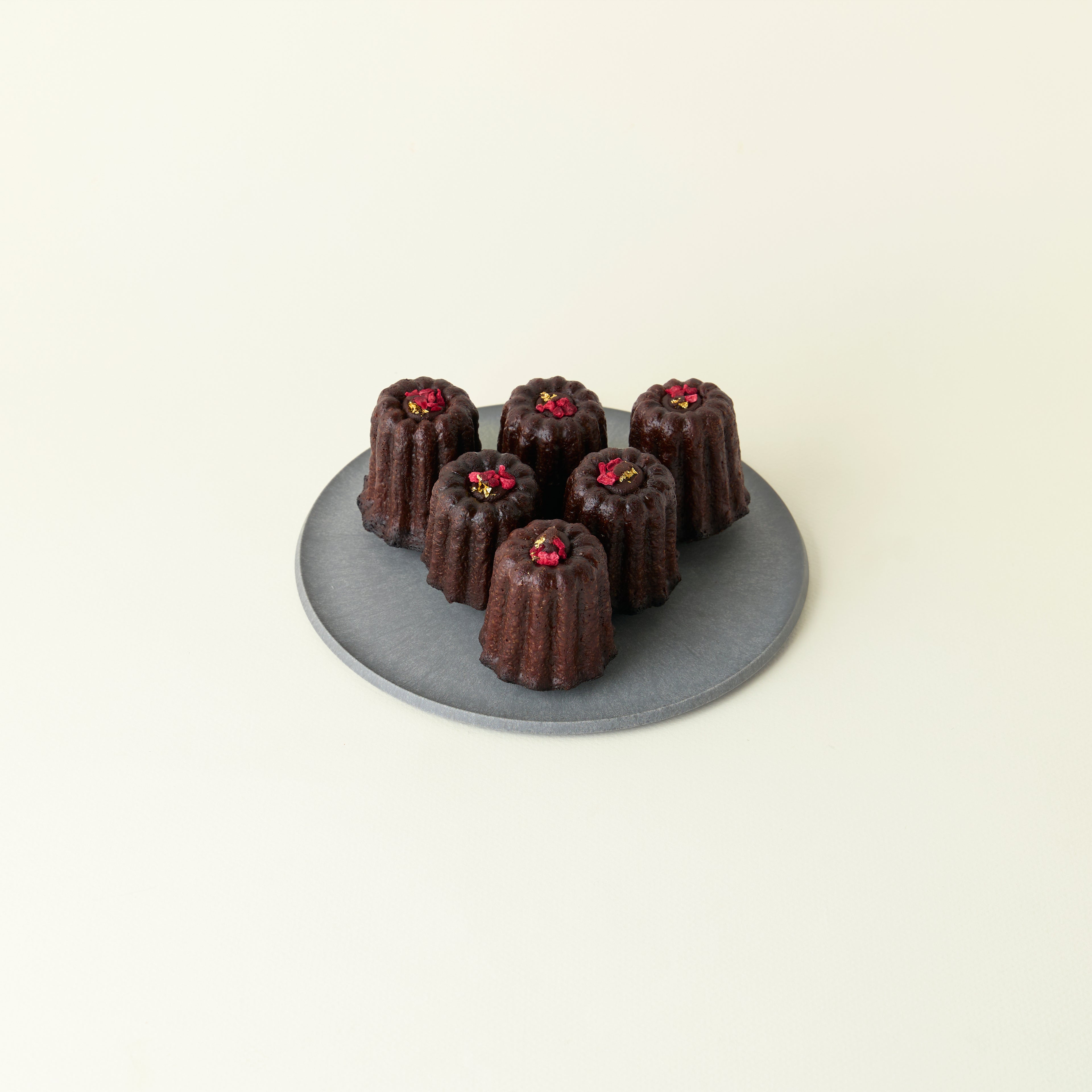 Chocolate canelés on a gray plate with a white background