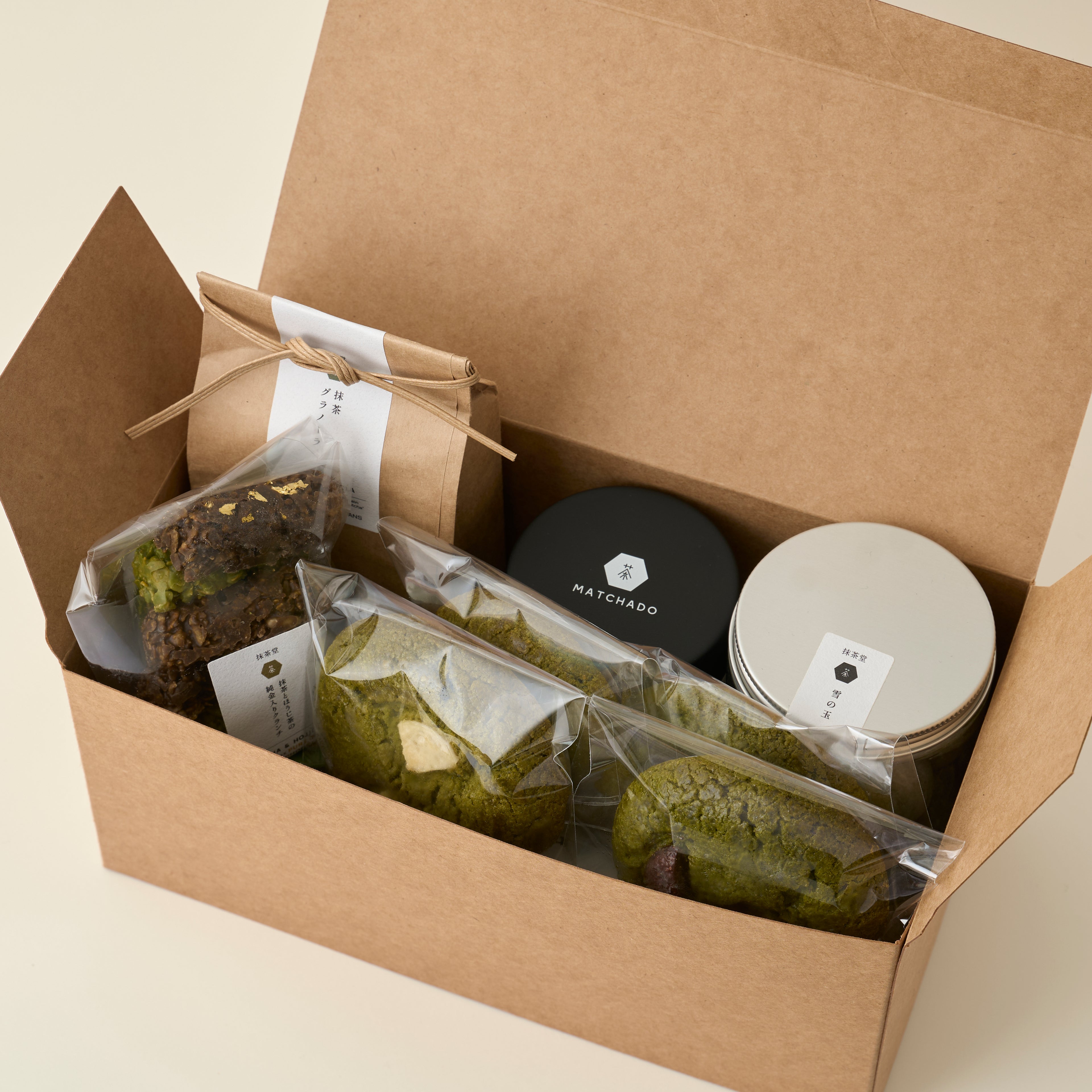 MATCHADO Vegan Sweets Box - Plant-Based Matcha & Hojicha Treats. Open brown box containing matcha green tea products on a beige background