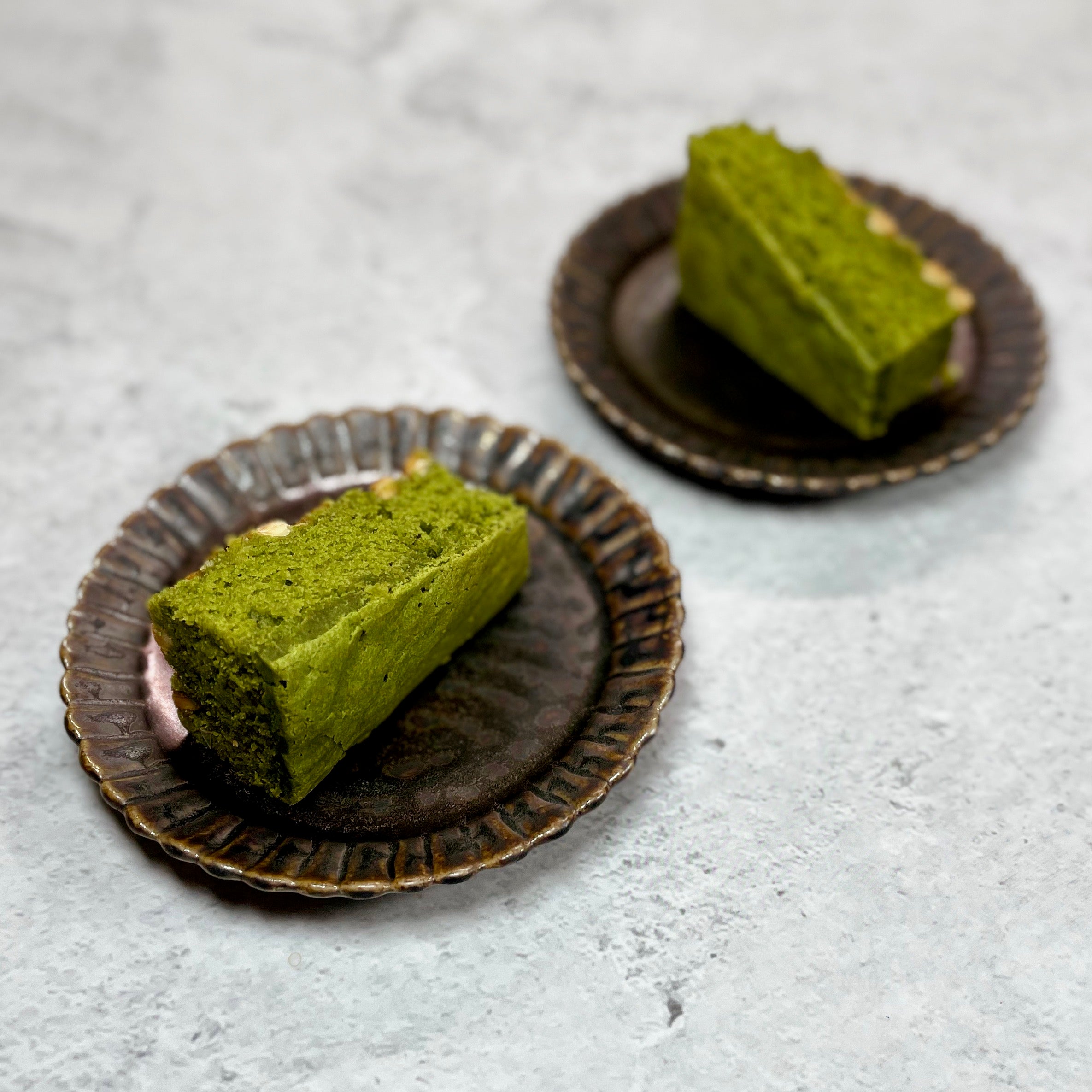 MATCHADO Gluten-Free Matcha Brownie – White Chocolate. Two pieces of cake are on the plates.