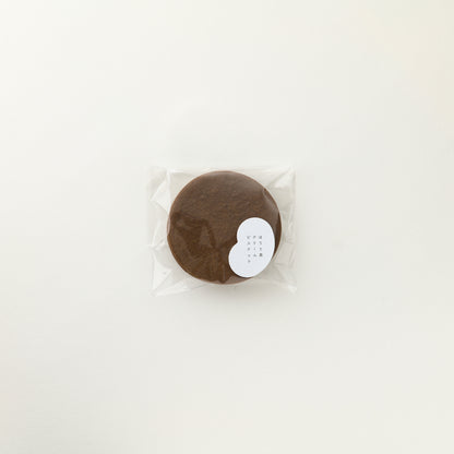 Round brown product in clear packaging on a white background