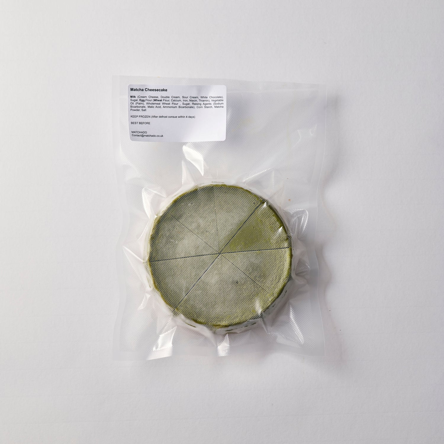 Matcha cheese wheel in clear plastic packaging on a white background