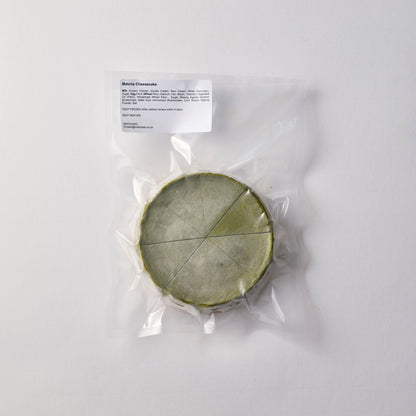 Matcha cheese wheel in clear plastic packaging on a white background