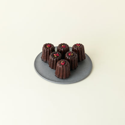Chocolate canelés on a gray plate with a white background
