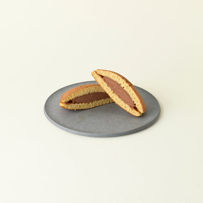 MATCHADO Miffy chocolate Dorayaki - Authentic Japanese Pancake - Fluffy &amp; Sweet Handmade Treat. Two halves of a dorayaki with chocolate filling on a gray plate against a beige background