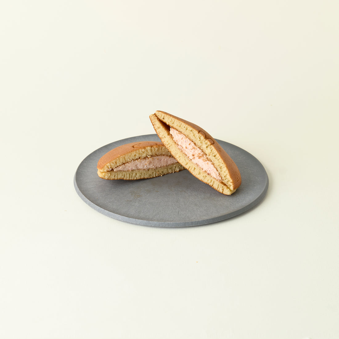 Two halves of a dorayaki on a gray plate against a light beige background
