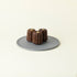 Three MATCHADO Matcha Canelés on a grey plate, topped with a smooth matcha cream. The dark caramelized crust contrasts with the rich, green tea infused centre.
