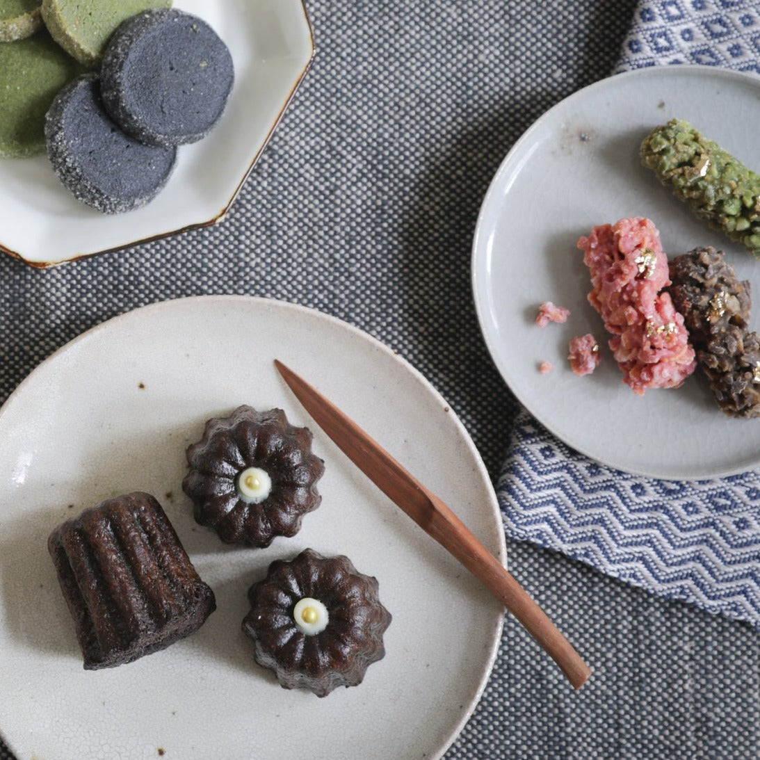 A variety of MATCHADO sweets served on elegant plates, featuring Matcha Canelés, cookies, and chocolate treats. A perfect Japanese-inspired tea time arrangement.