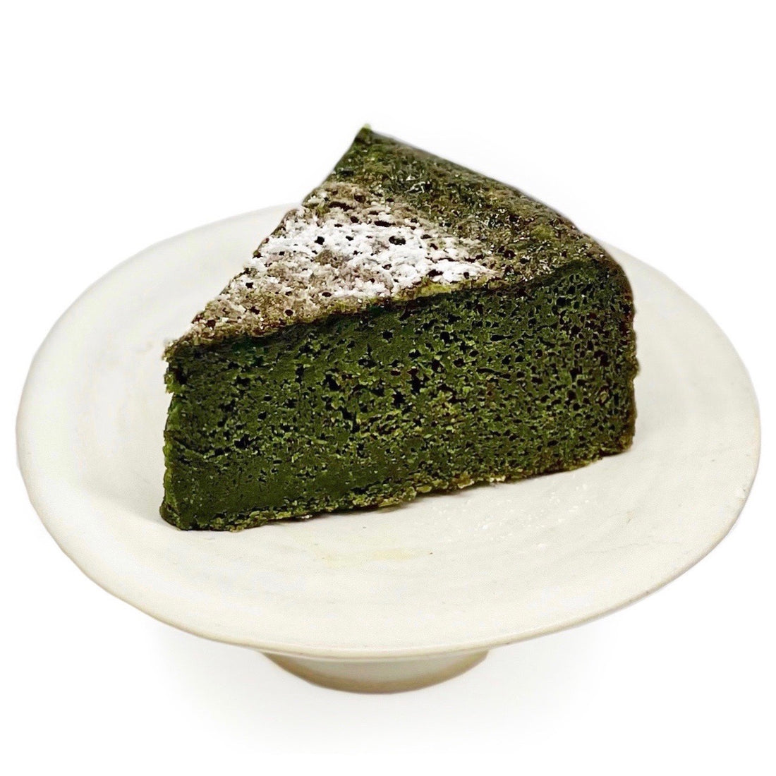 A gift set featuring a whole MATCHADO Matcha Gâteau Chocolat and a sleek silver cake server. A sliced piece of the cake is shown to display its rich texture.